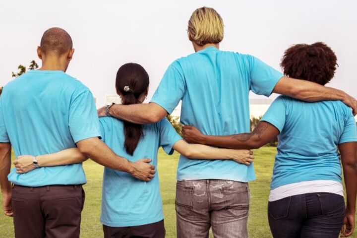 Symbolbild: Vier Menschen stehen Arm in Arm. 