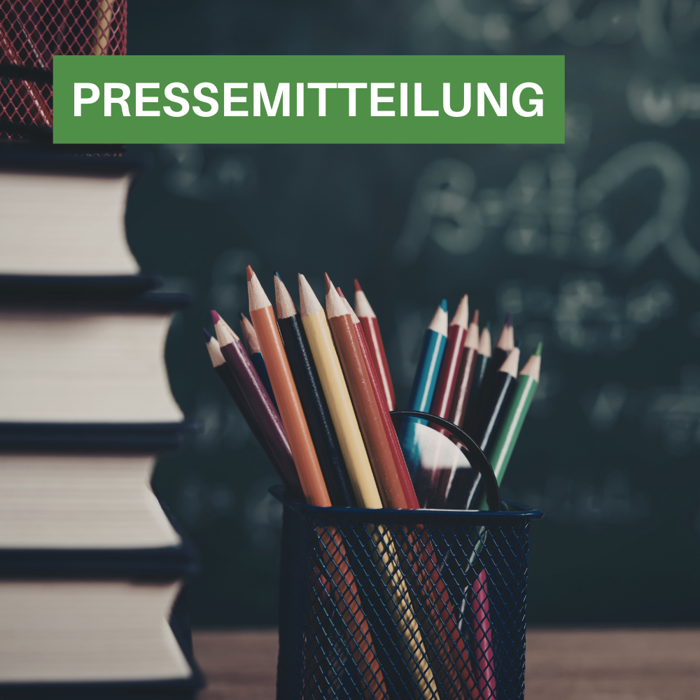 Vor einer Tafel ein Stapel Bücher mit einigen Stiften. Darauf der Text:"Pressemitteilung"
